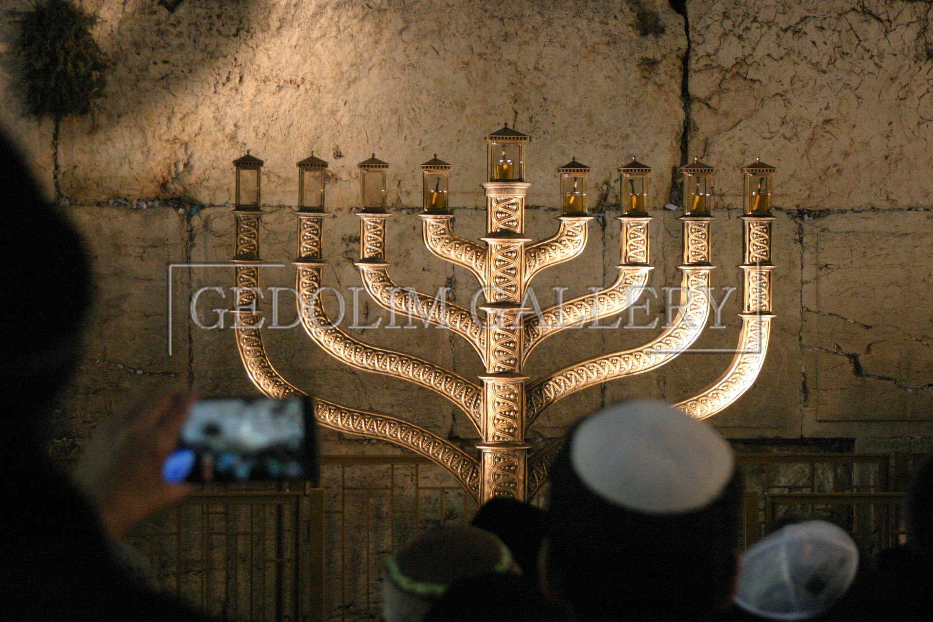 A man is taking a picture of a menorah with a cell phone