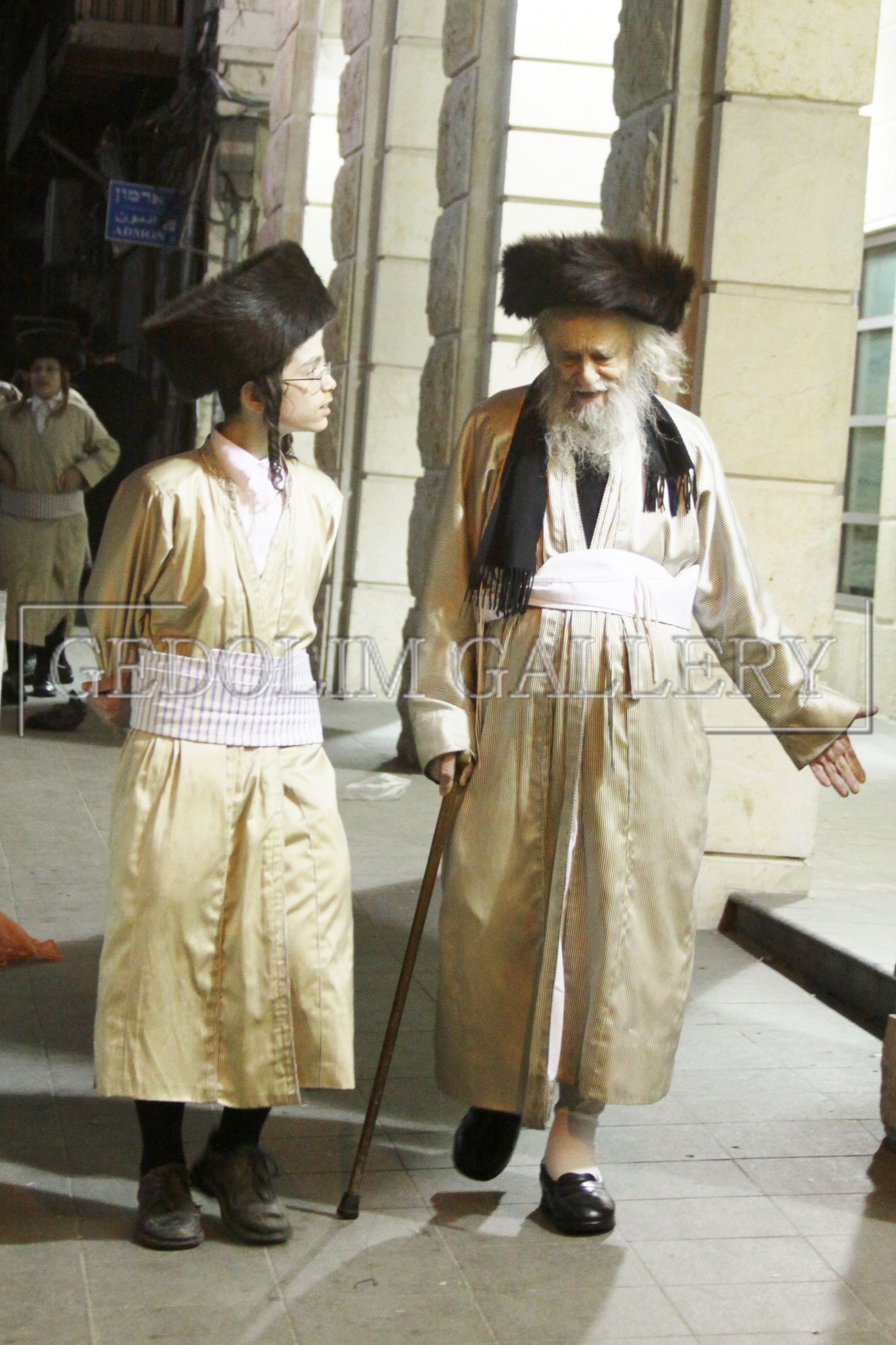 A man with a beard and a cane is walking with another man