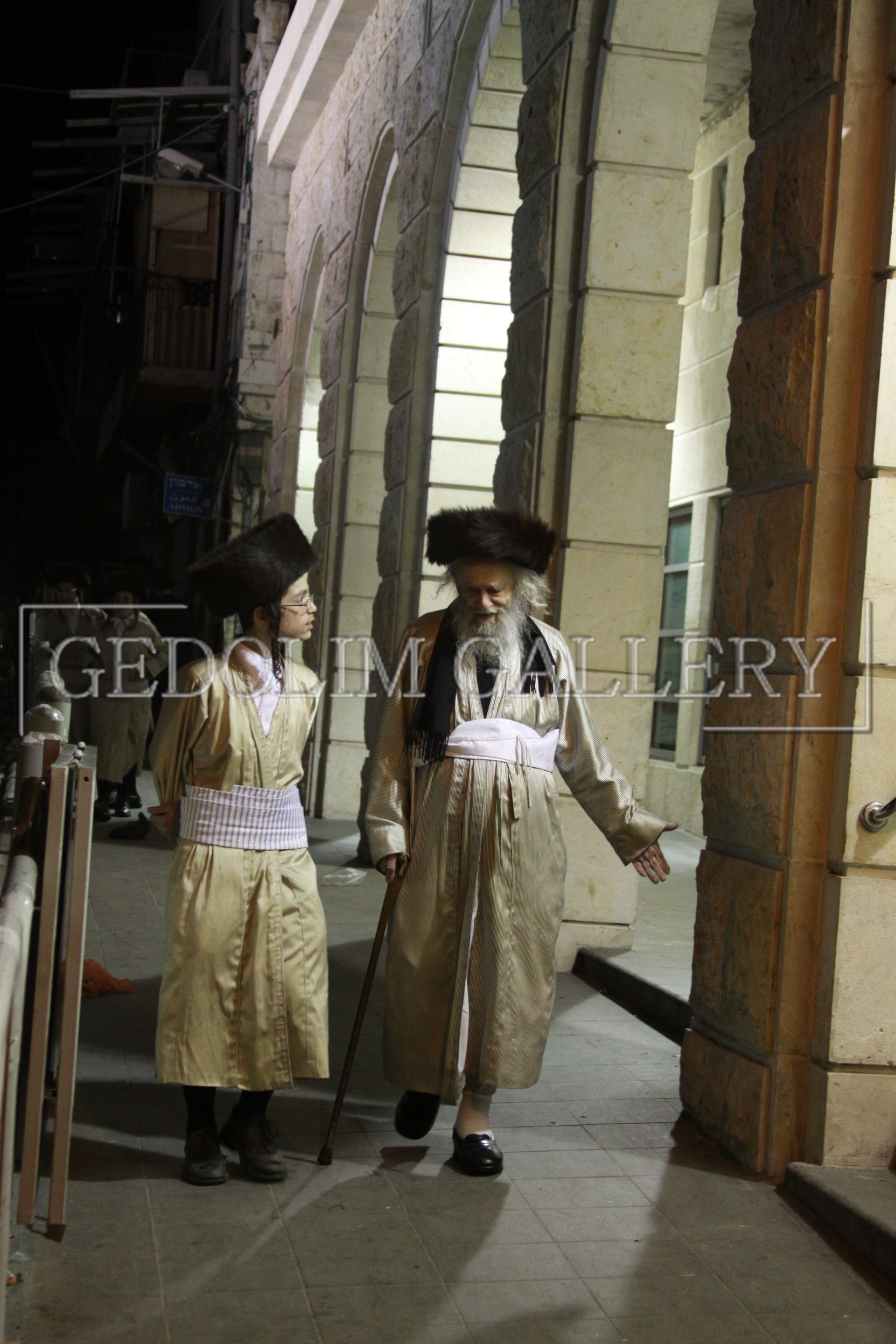 A man and a boy are walking down a sidewalk.