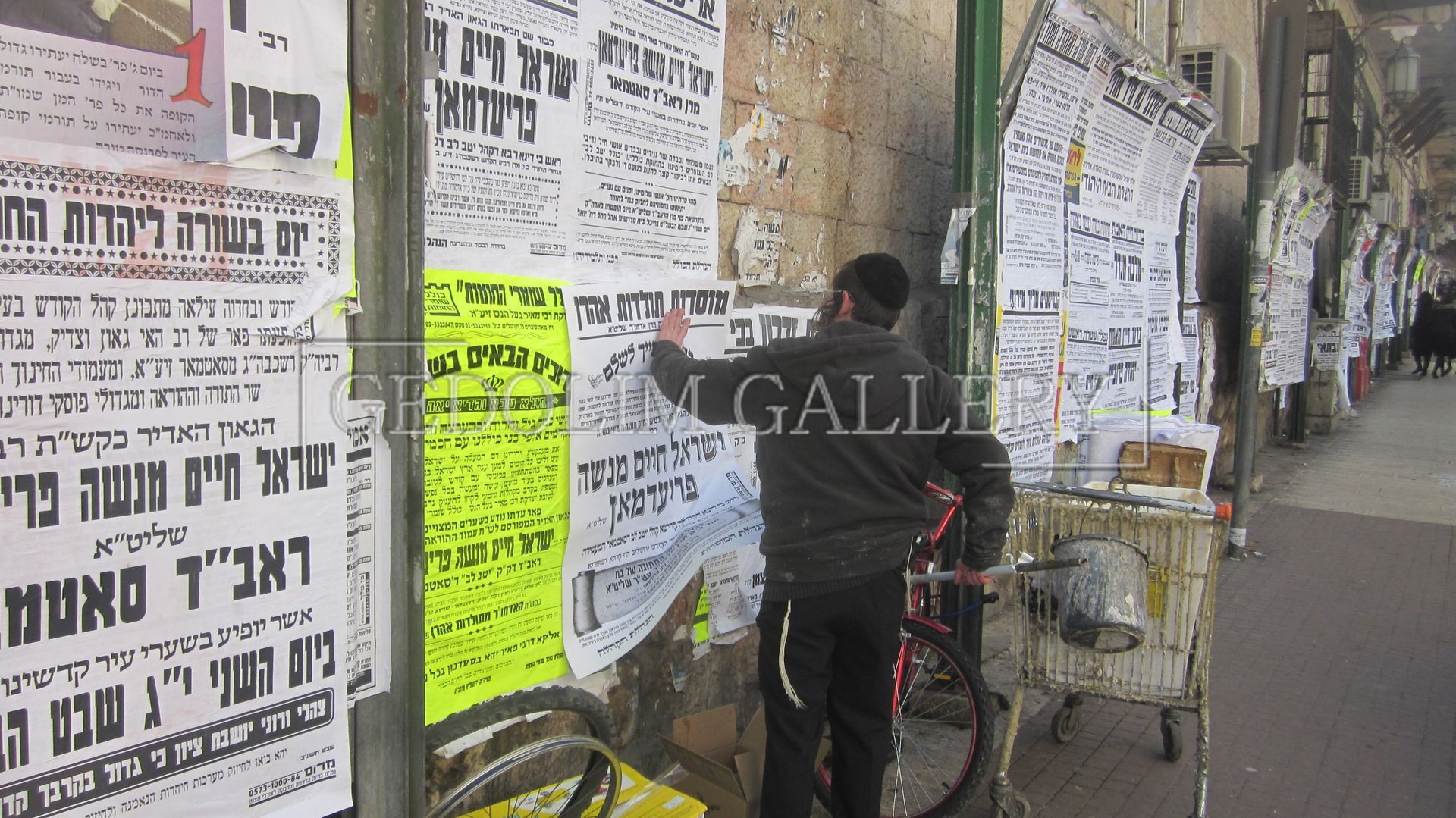 A man is putting a flyer on a wall that says galler