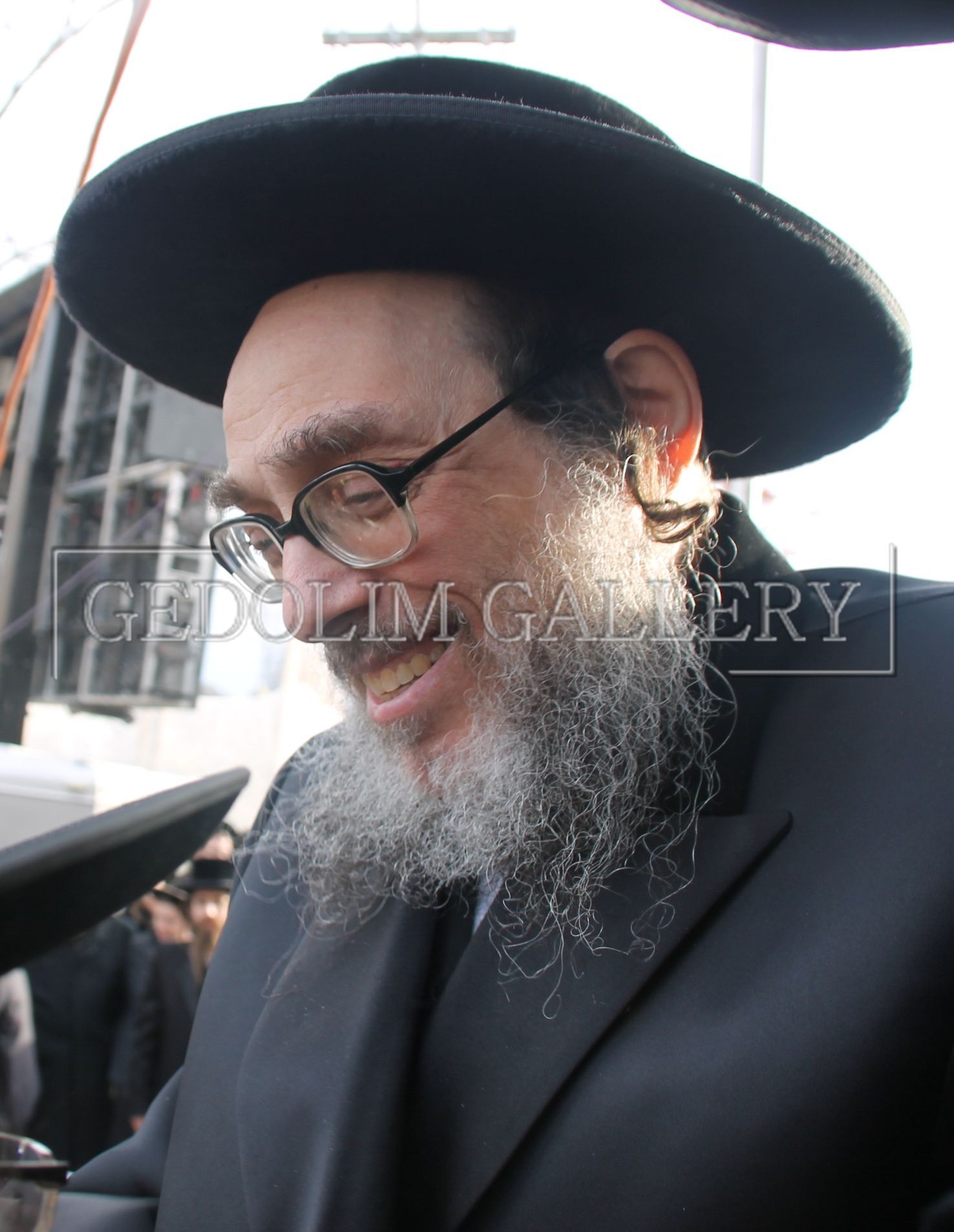 A man with a beard wearing a hat and glasses is taken by gedolin gallery