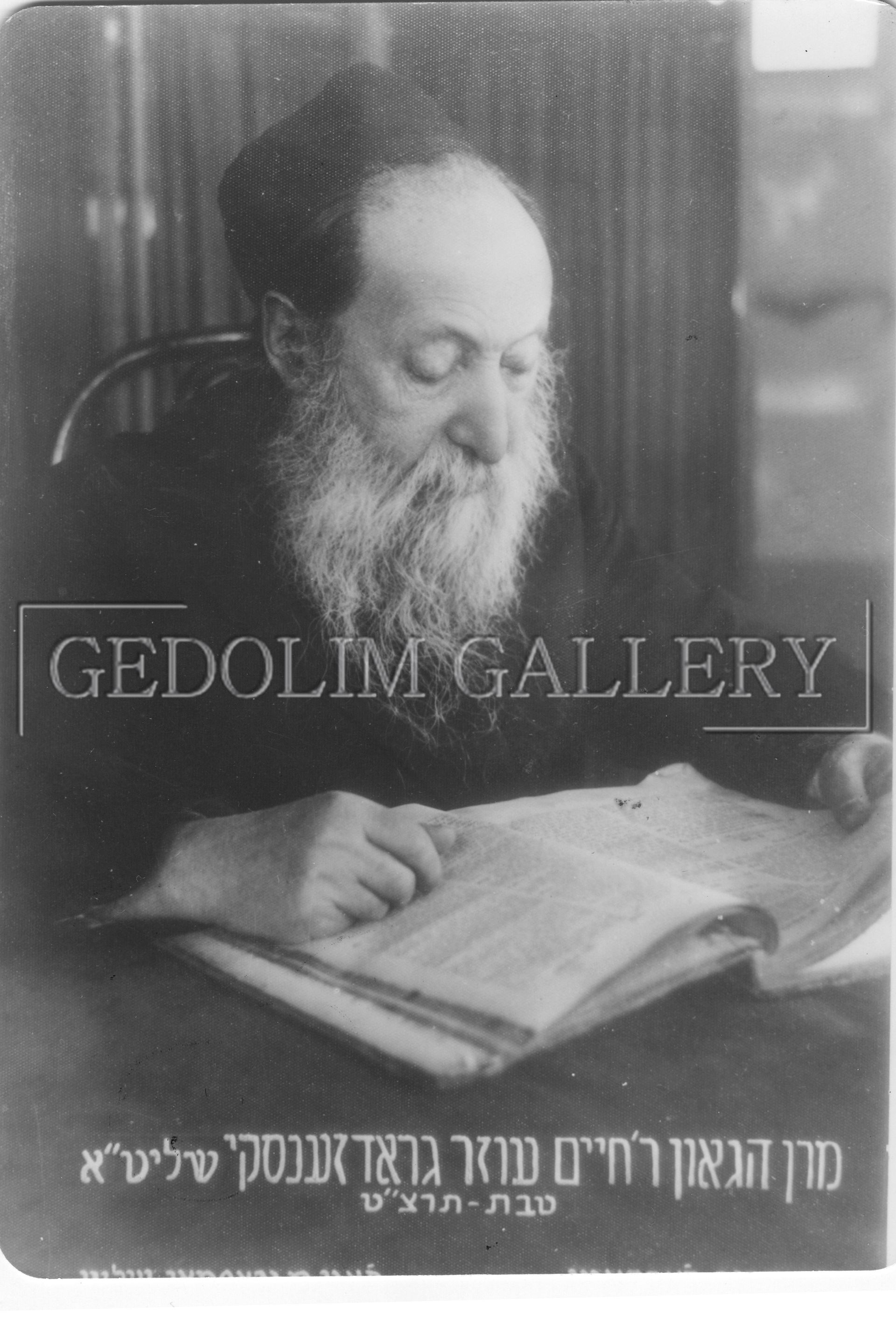 A man with a beard is sitting at a table reading a book.