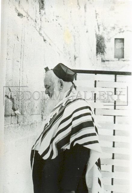 A black and white photo of a jewish man standing in front of a wall