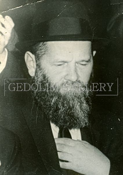 A black and white photo of a man with a beard wearing a hat and tie