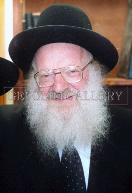 A man with a beard and glasses is wearing a black hat