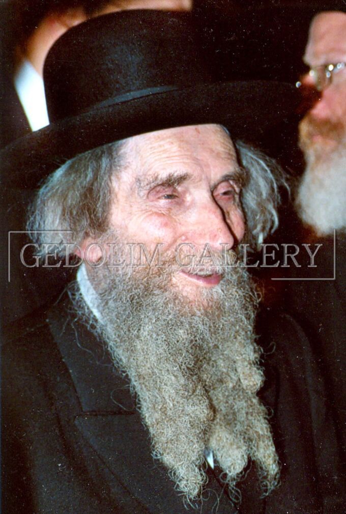 A man with a beard and a hat is smiling.