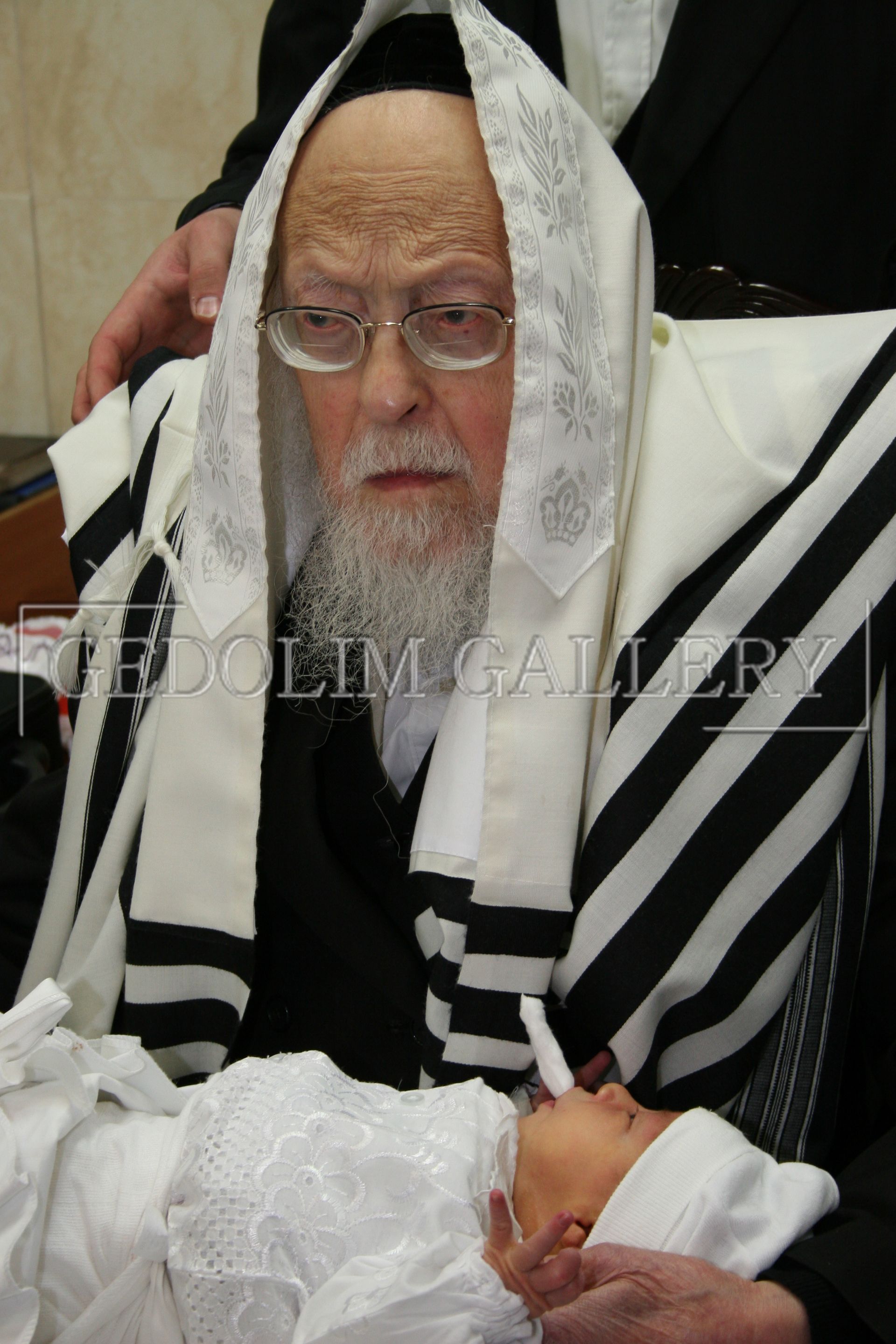 A man in a black and white striped robe is holding a baby