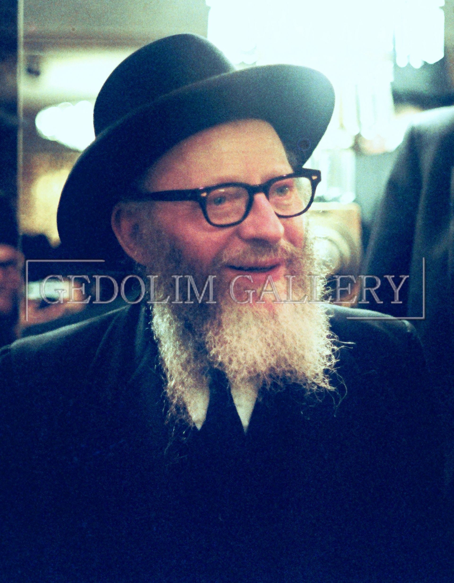A man with a beard and glasses is wearing a hat and tie