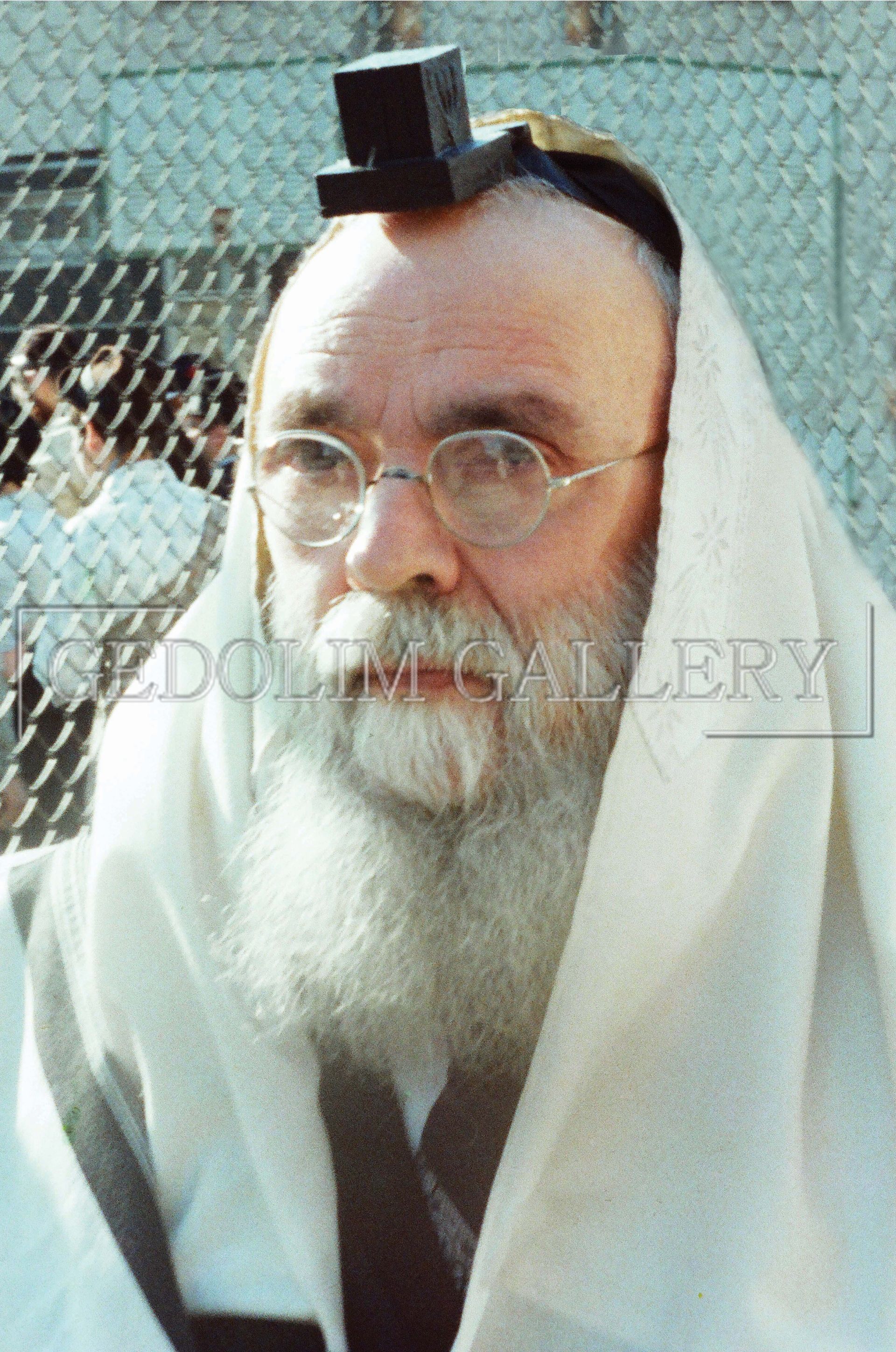 A man with a beard wearing glasses and a torah on his head
