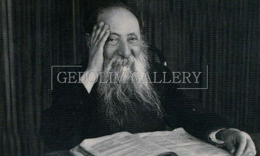 A man with a beard is sitting at a table holding a piece of paper.
