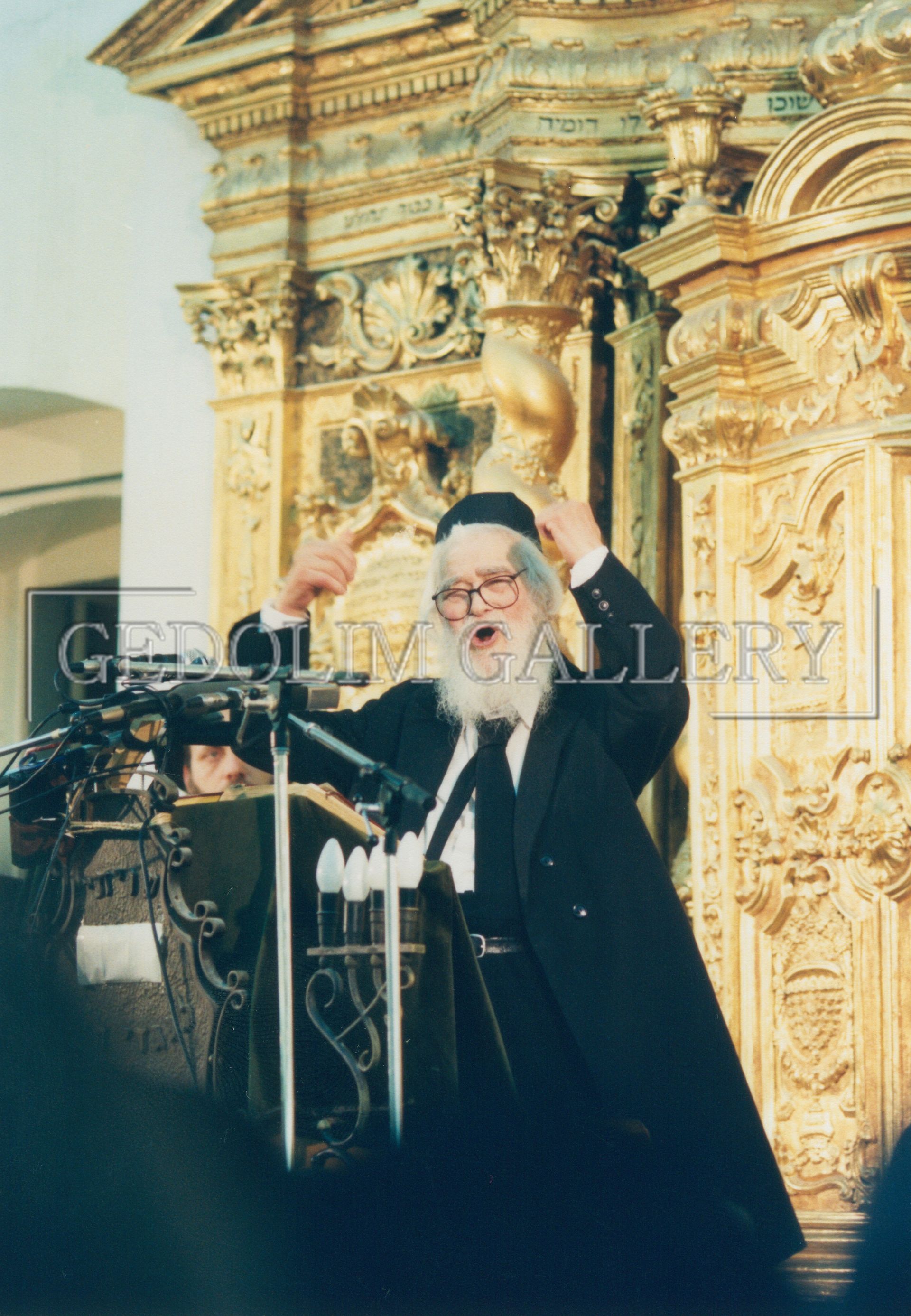 A man with a beard is giving a speech at a podium with the word gallery on the bottom