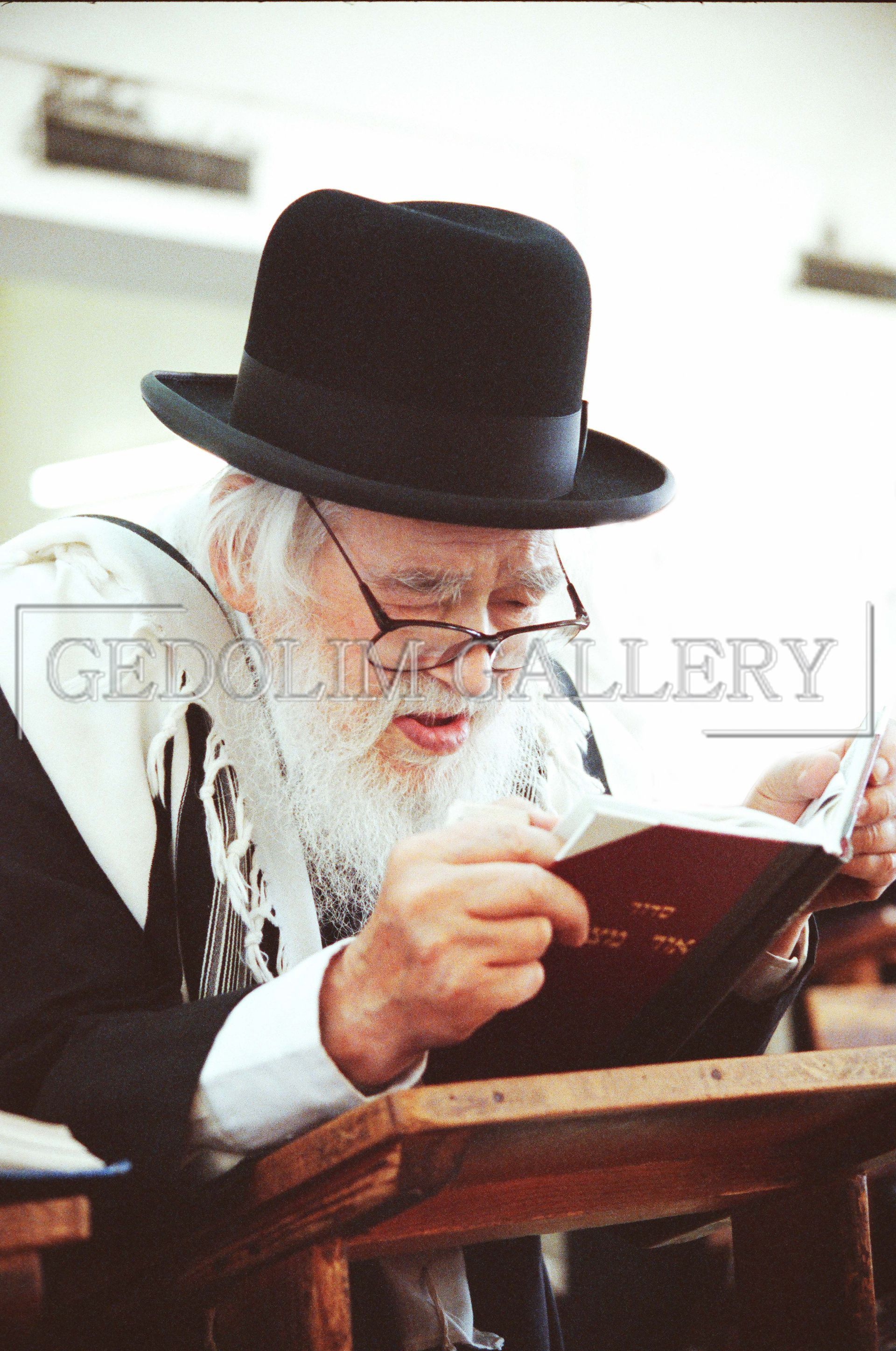 A man wearing a black hat and glasses is reading a book