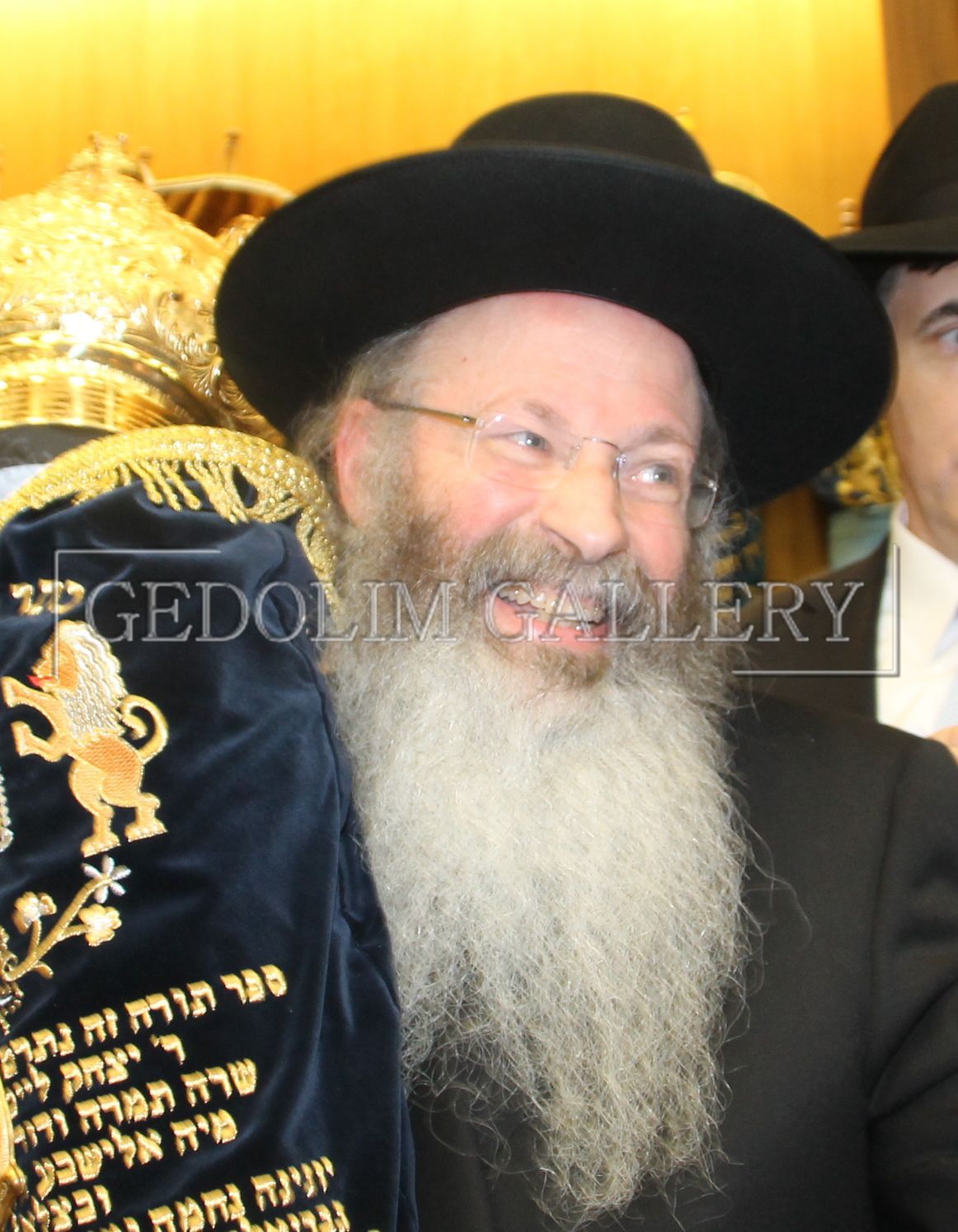 A man with a beard is holding a scroll with hebrew writing on it