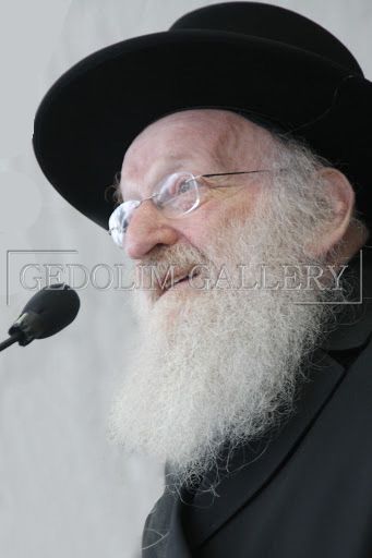 A man with a beard and glasses is speaking into a microphone.