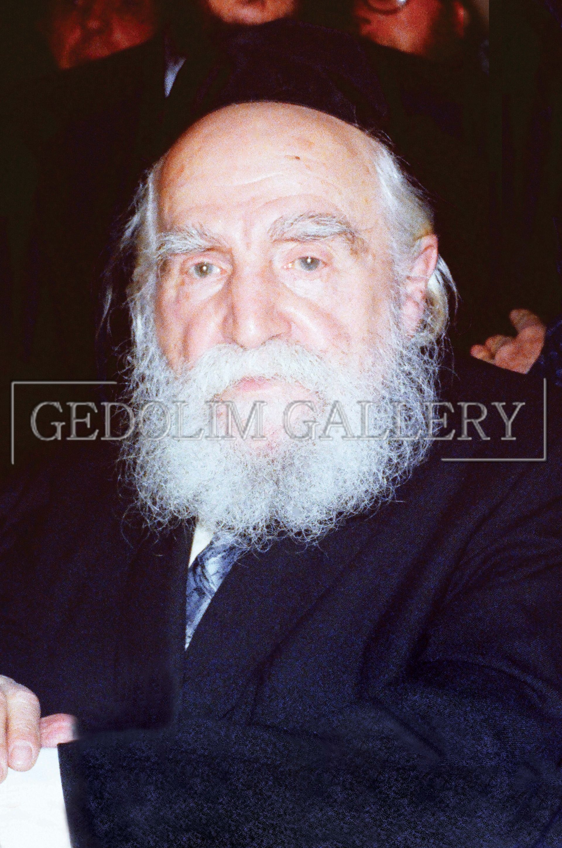 A man with a beard is wearing a black jacket and tie.