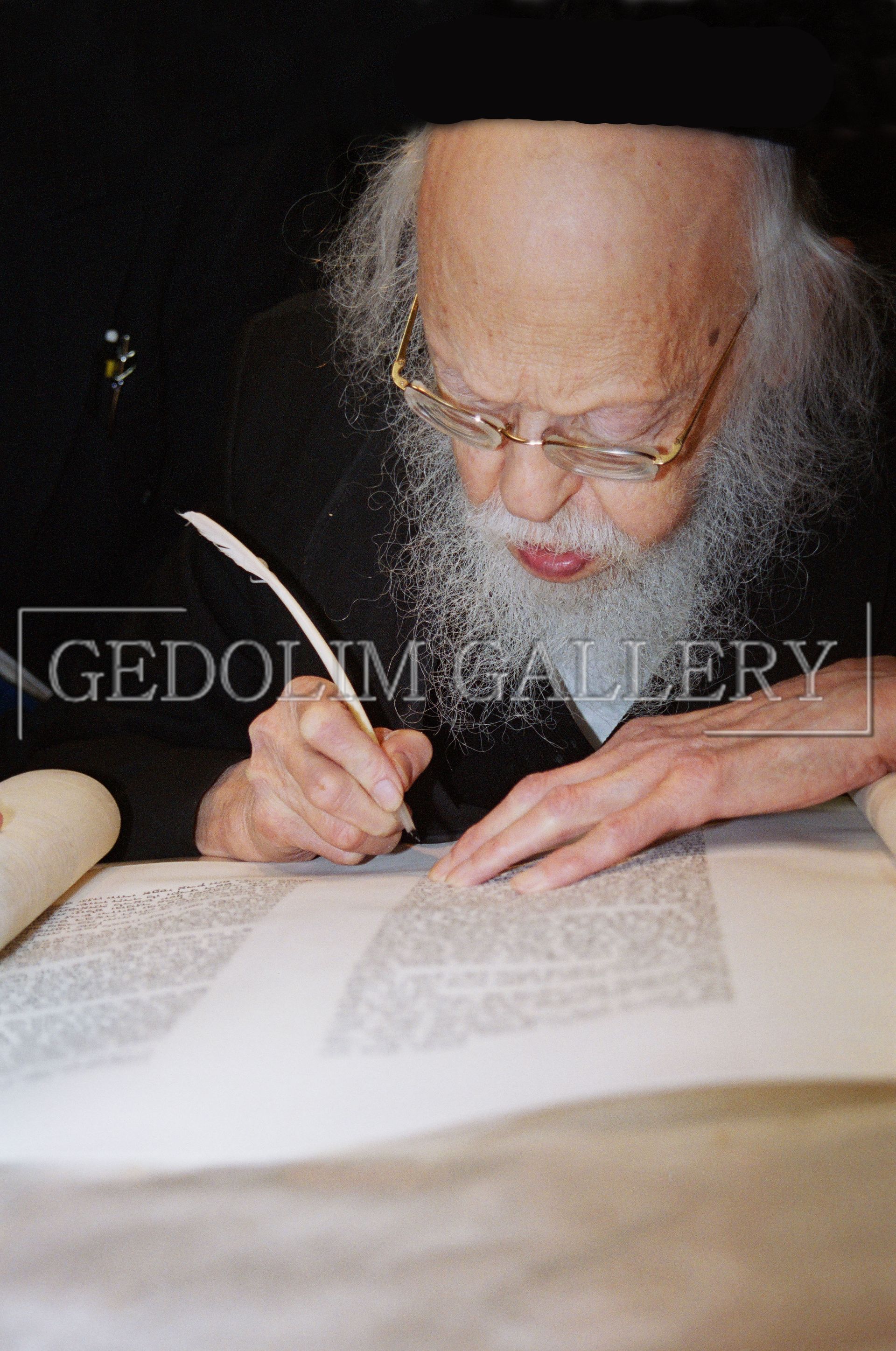 A man with a beard is writing on a piece of paper with a pen.