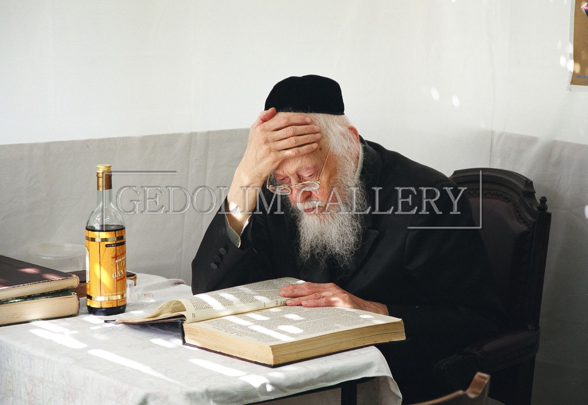 A man with a beard sits at a table reading a book
