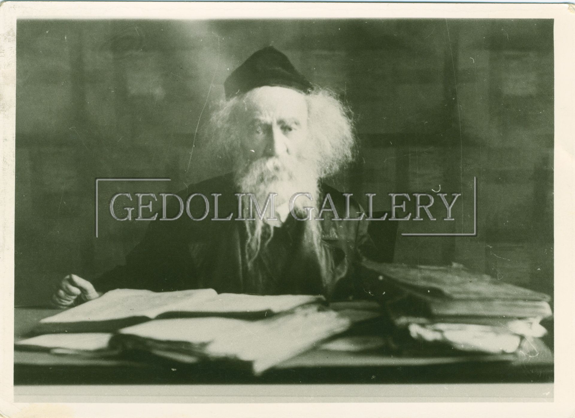 A black and white photo of a man with a beard sitting at a desk.
