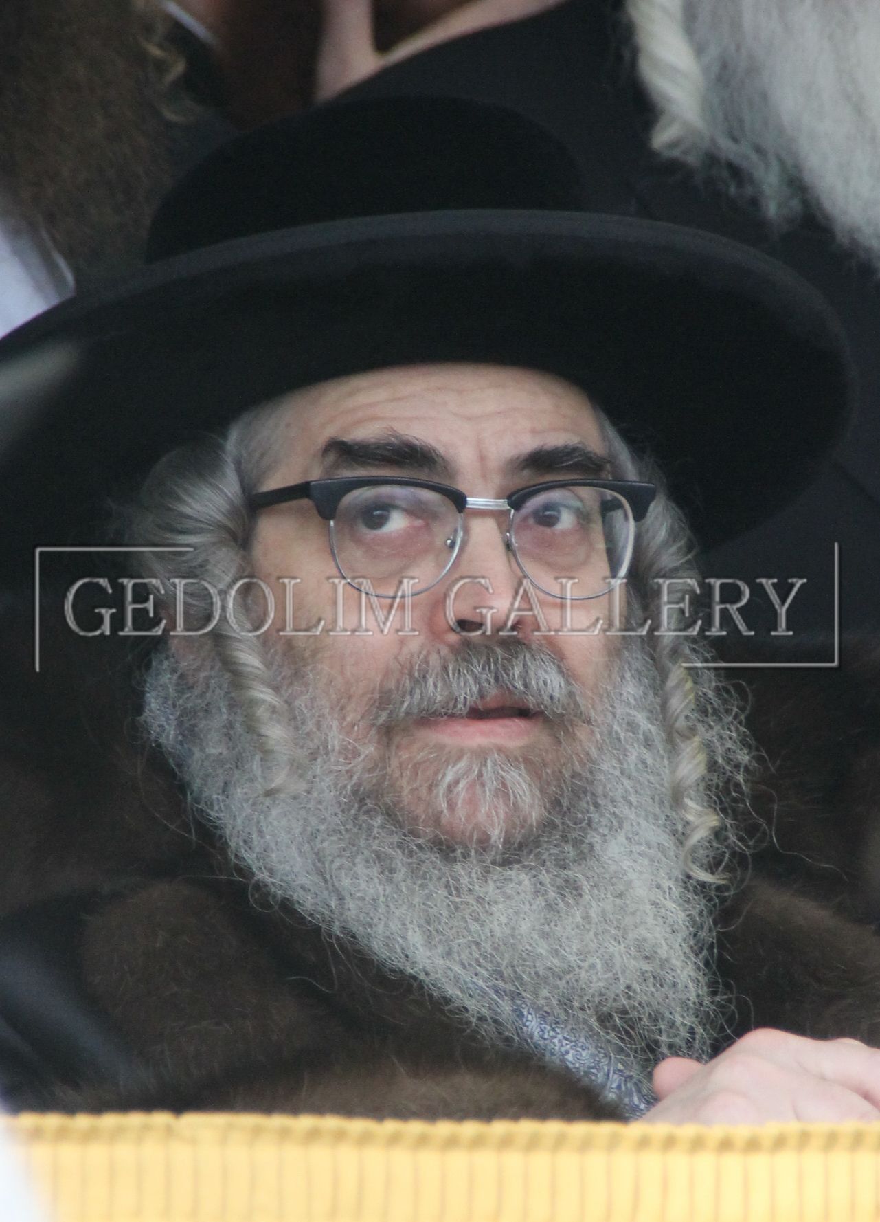 A man with a beard and glasses is wearing a black hat