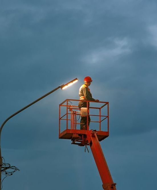 A Man Is Working On A Street Light On A Crane — Macleay Air In West Kempsey, NSW