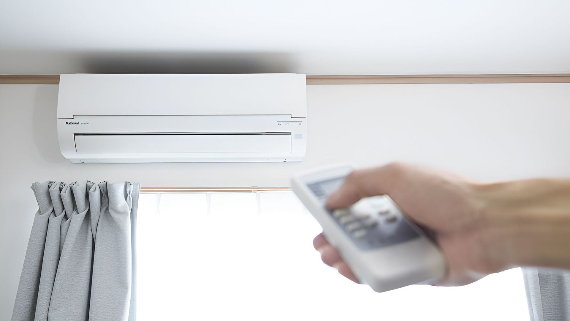 A Person Is Holding A Remote Control In Front Of An Air Conditioner — Macleay Air In Macksville, NSW