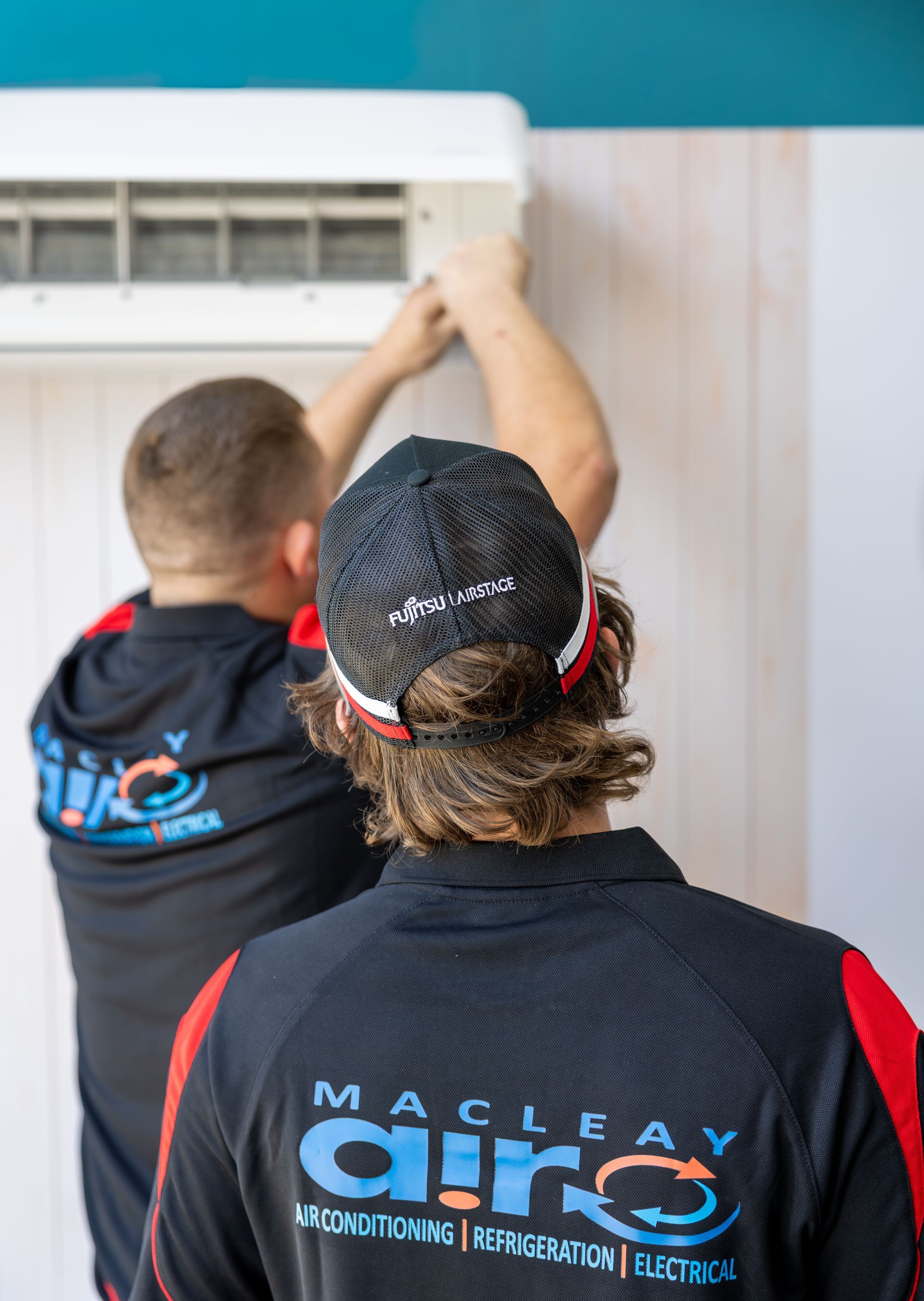 A Man Is Cleaning The Inside Of An Air Conditioner — Macleay Air In West Kempsey, NSW