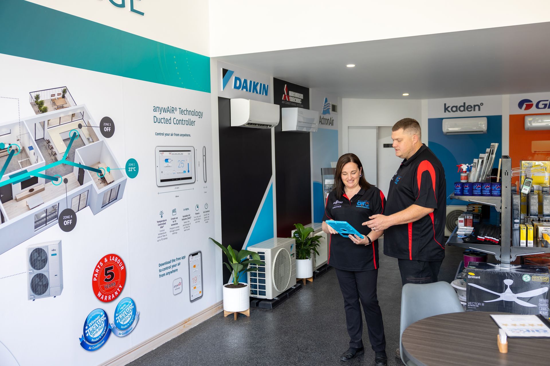 A Man Is Using A Drill To Fix An Air Conditioner — Macleay Air In West Kempsey, NSW