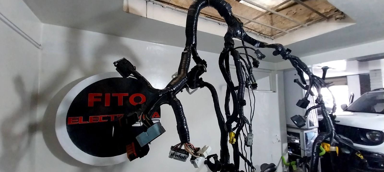 Bicicleta eléctrica Fito negra con cables colgando en una habitación que parece un garaje.