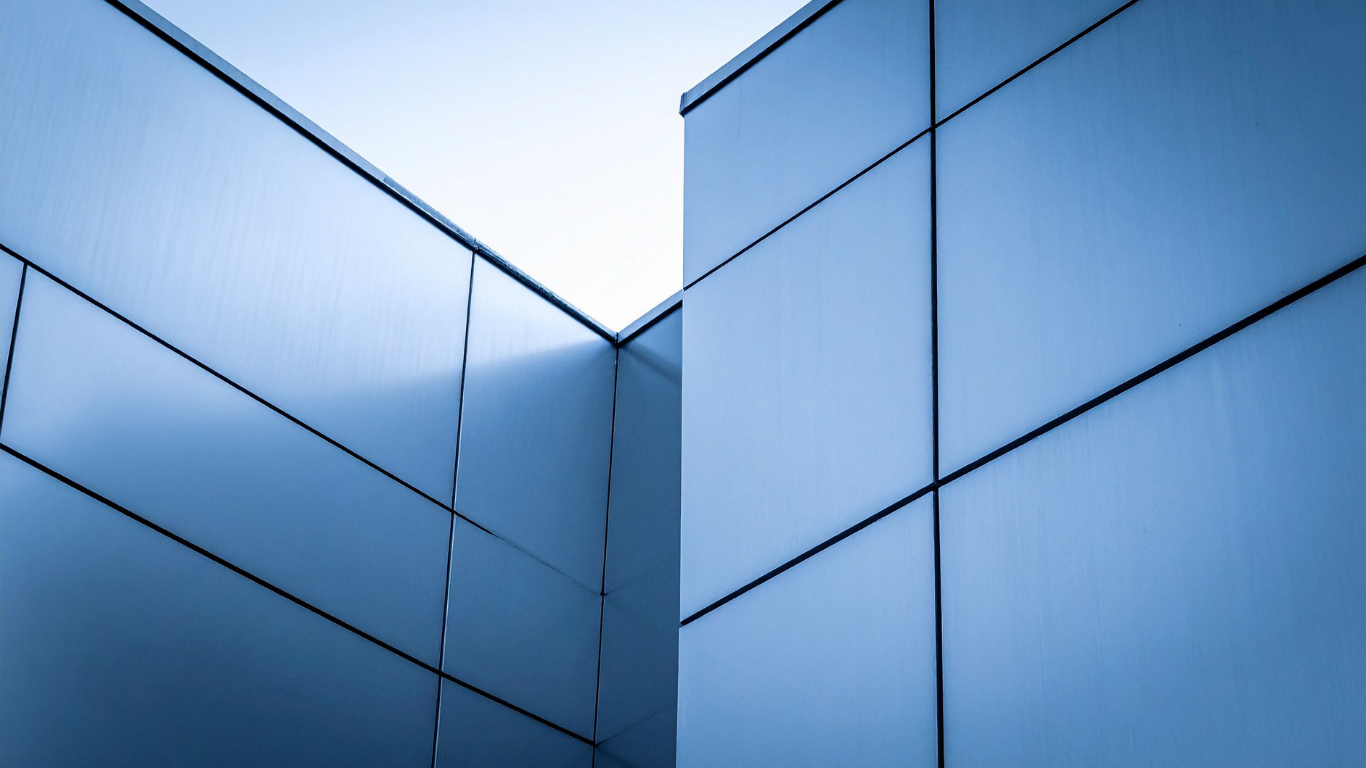 Blue metallic building exterior, geometric design, corner view, bright sky.