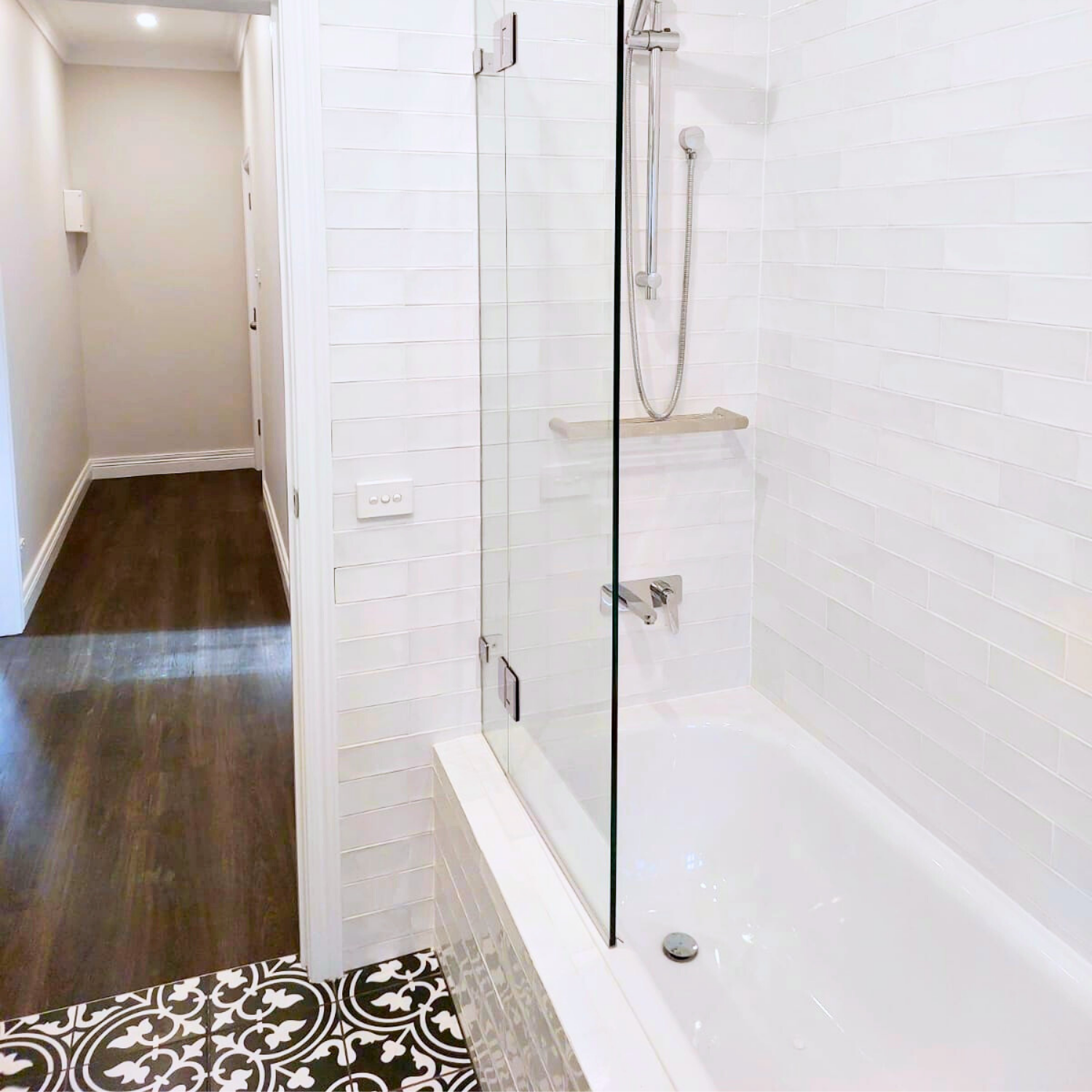 Bathroom With a White Bathtub, Glass Shower Screen, and Patterned Floor Tiles — Elimar Construction in Goulburn, NSW