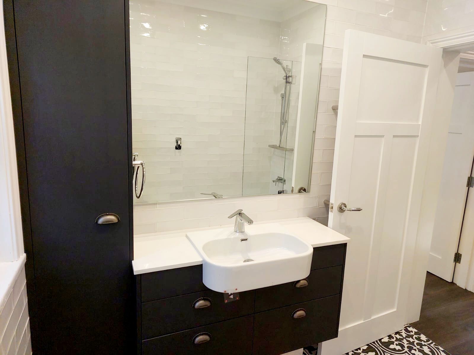 Modern Bathroom With Dark Gray Vanity, White Sink, Large Mirror, and Black Storage Cabinet — Elimar Construction in Goulburn, NSW