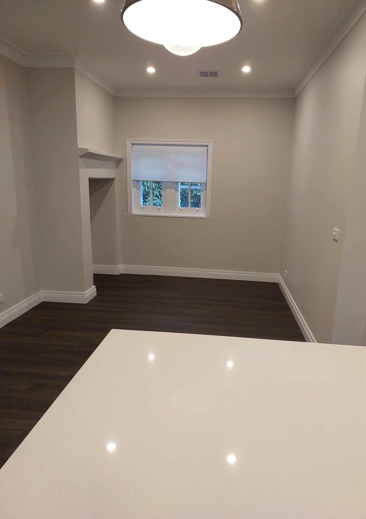 Empty Room With Dark Wood Floor, Light Gray Walls, White Trim, and a White Countertop in the Foreground — Elimar Construction in Goulburn, NSW