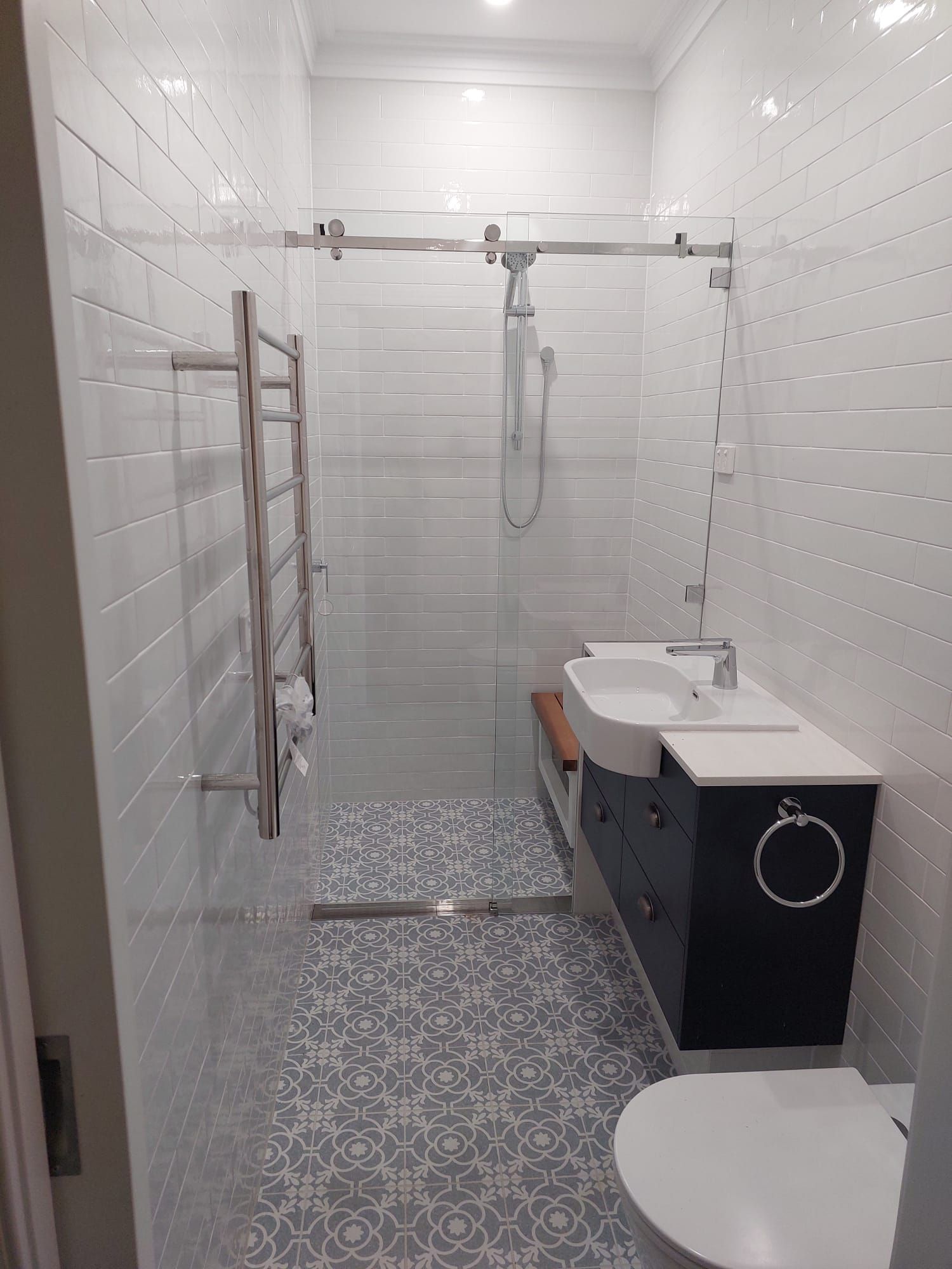 Modern Bathroom With White and Patterned Tile, Glass Shower, Vanity, and Toilet — Elimar Construction in Goulburn, NSW