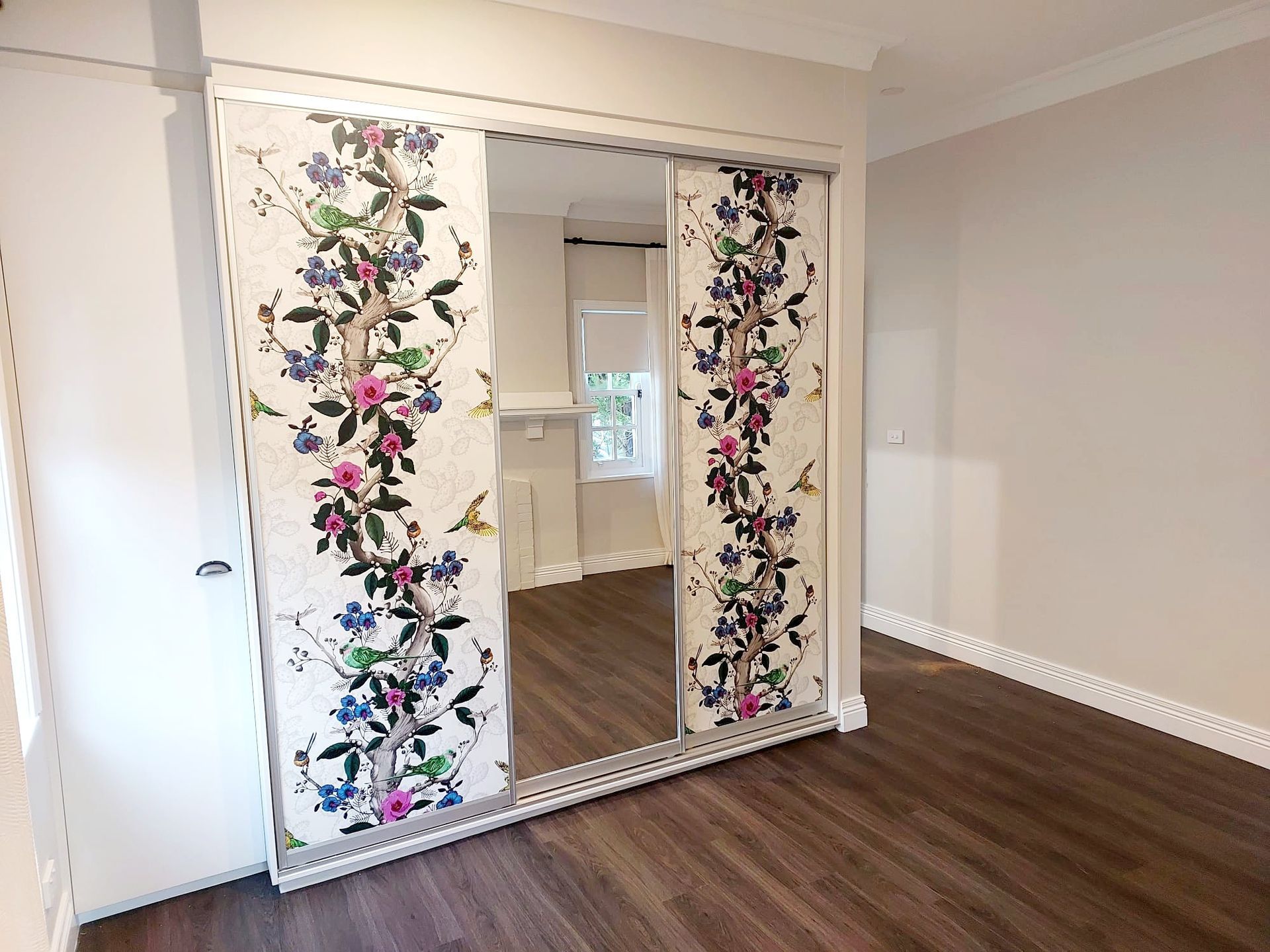 Bedroom With Floral Sliding Closet Doors and Wood Floors — Elimar Construction in Goulburn, NSW