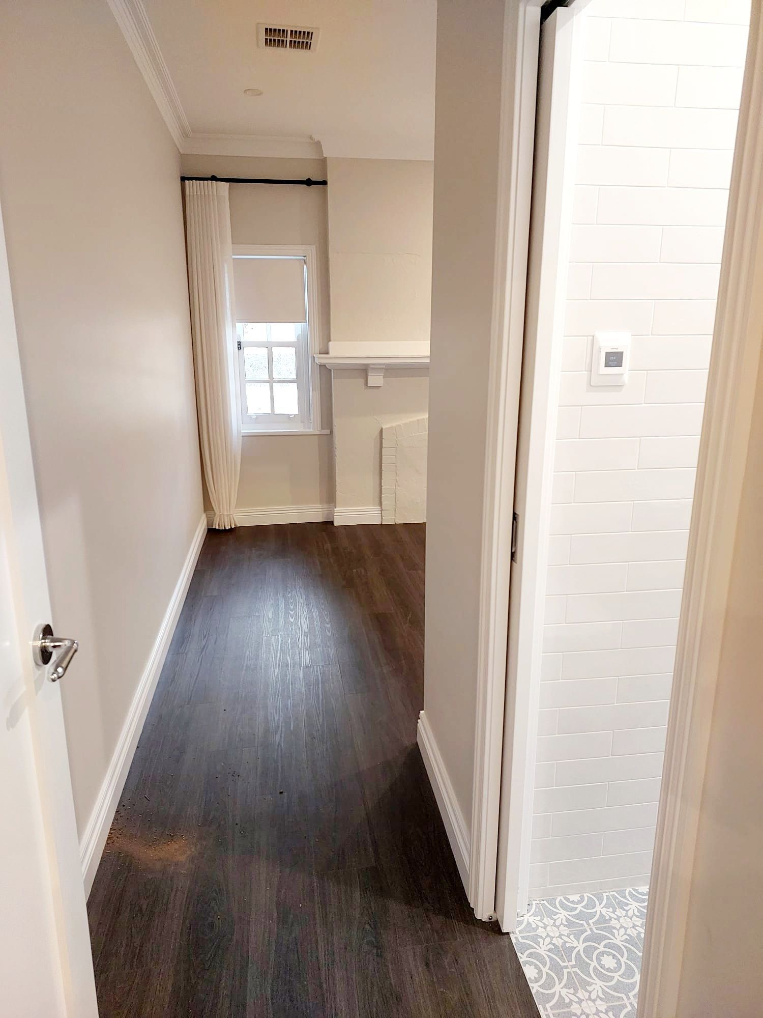 Narrow Hallway With Dark Wood Floor, Light Walls, and a Doorway to a Tiled Bathroom — Elimar Construction in Goulburn, NSW