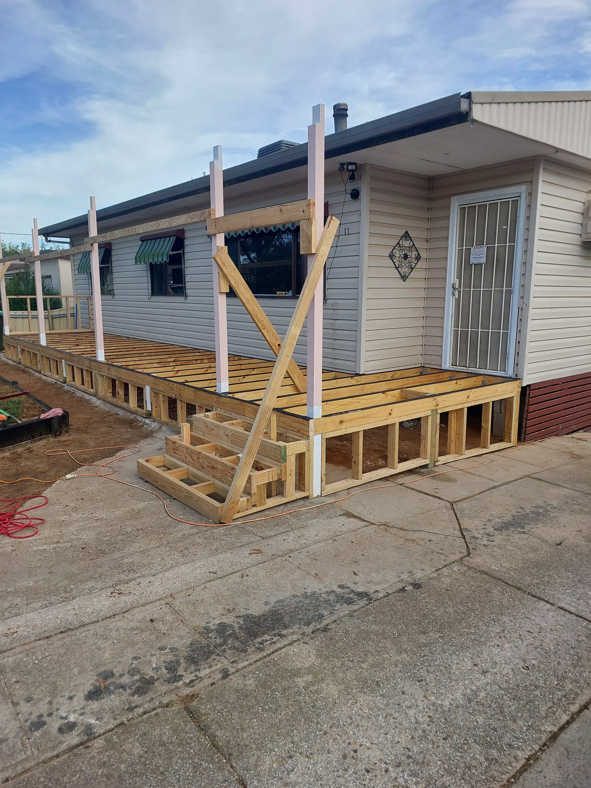 A Mobile Home With a Wooden Deck Being Built on the Side of It — Elimar Construction in Goulburn, NSW