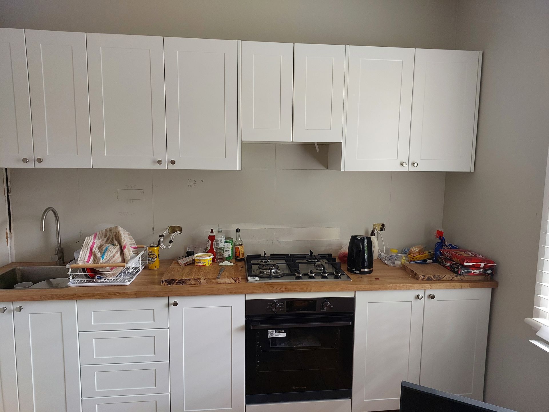 A Kitchen With White Cabinets, a Stove, and a Sink — Elimar Construction in Goulburn, NSW