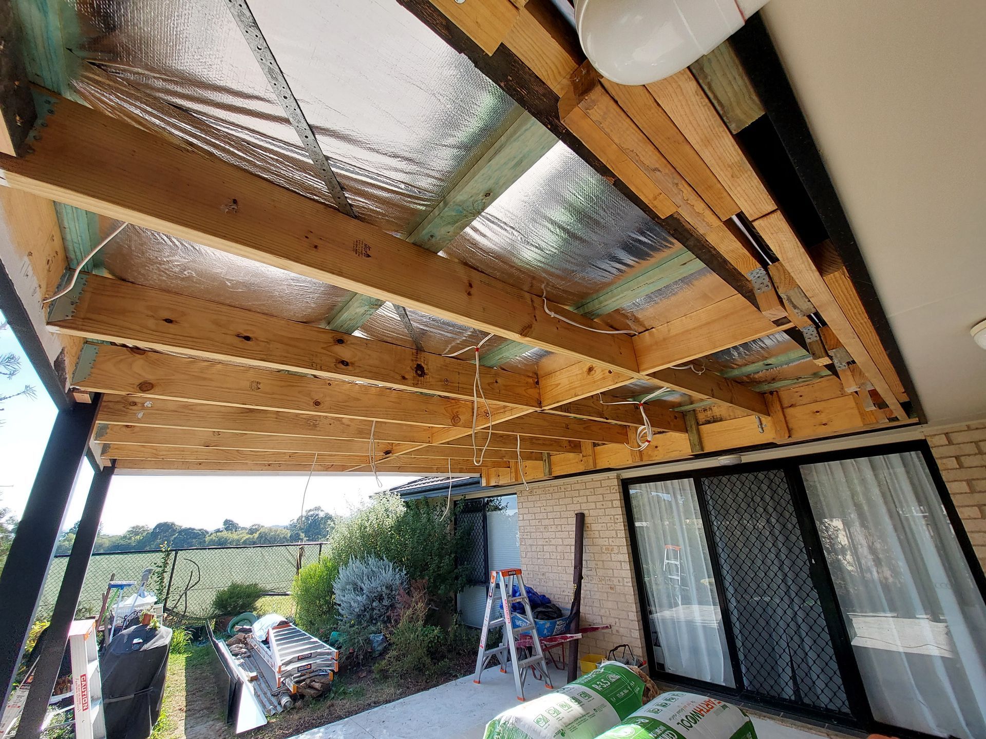 View of a Partially Constructed Patio Ceiling With Exposed Wooden Beams, Insulation, and Electrical Wiring — Elimar Construction in Goulburn, NSW