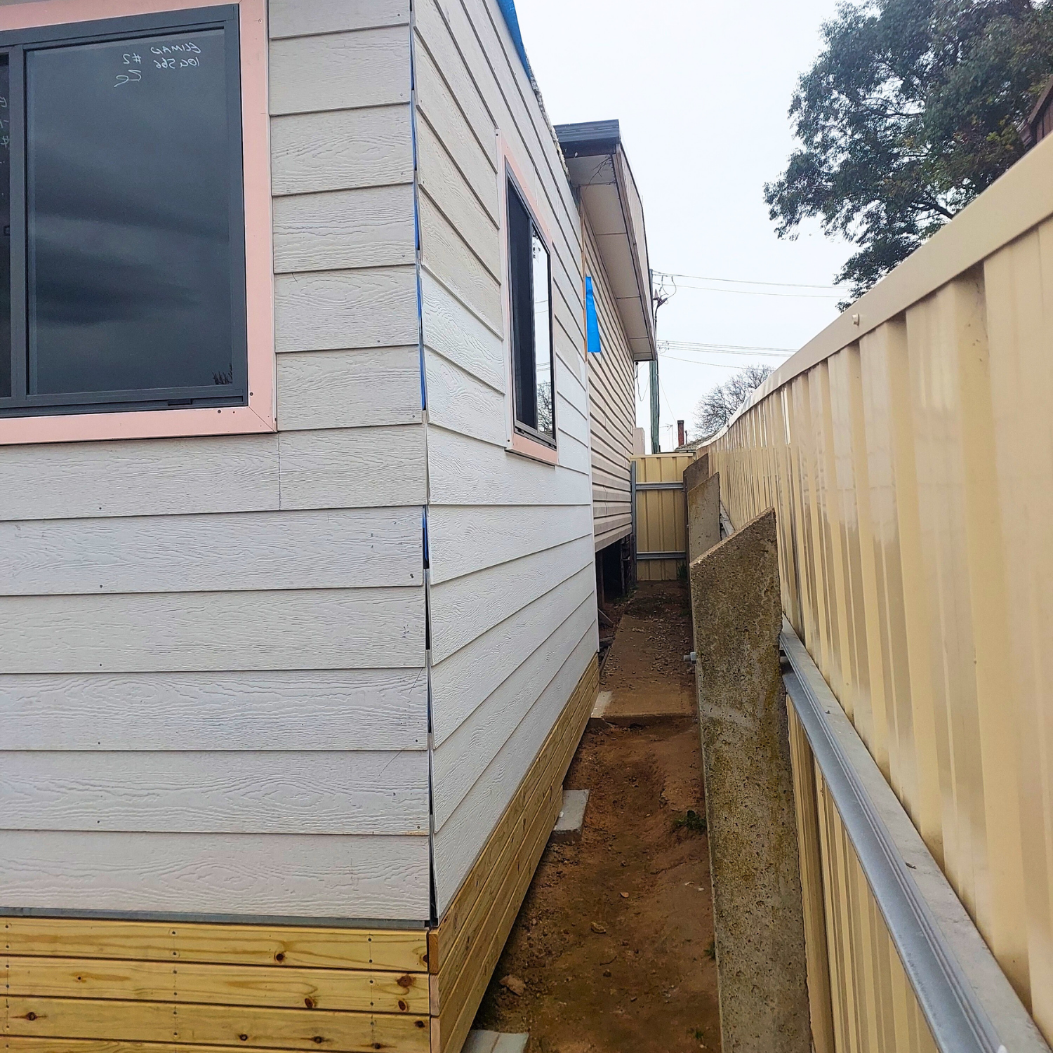 Exterior of a Building With Light Gray Siding Next to a Tan Fence — Elimar Construction in Goulburn, NSW