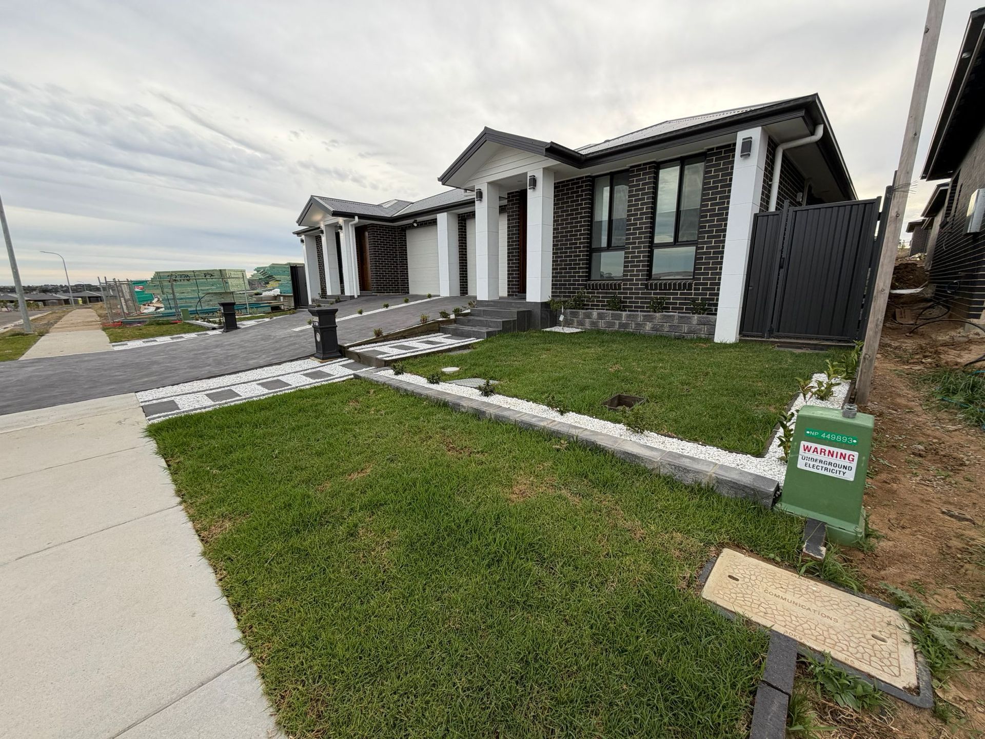 Modern house with a green lawn, sidewalk, and stone-bordered yard on a suburban street — Elimar Construction in Goulburn, NSW
