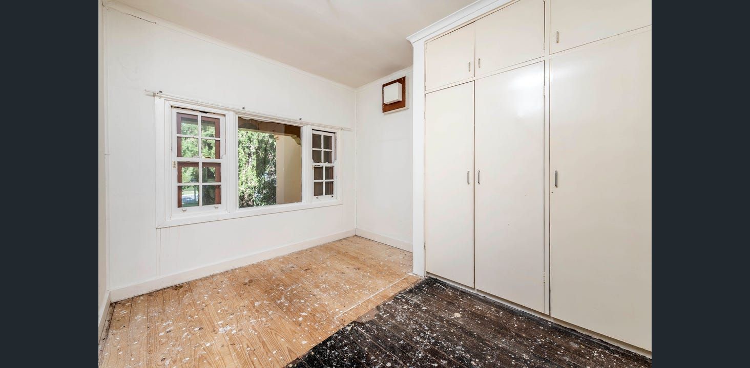 Bright Room With a Large Window and Built-in White Cabinets. Wooden Floor and a Dark Rug Are Present — Elimar Construction in Goulburn, NSW
