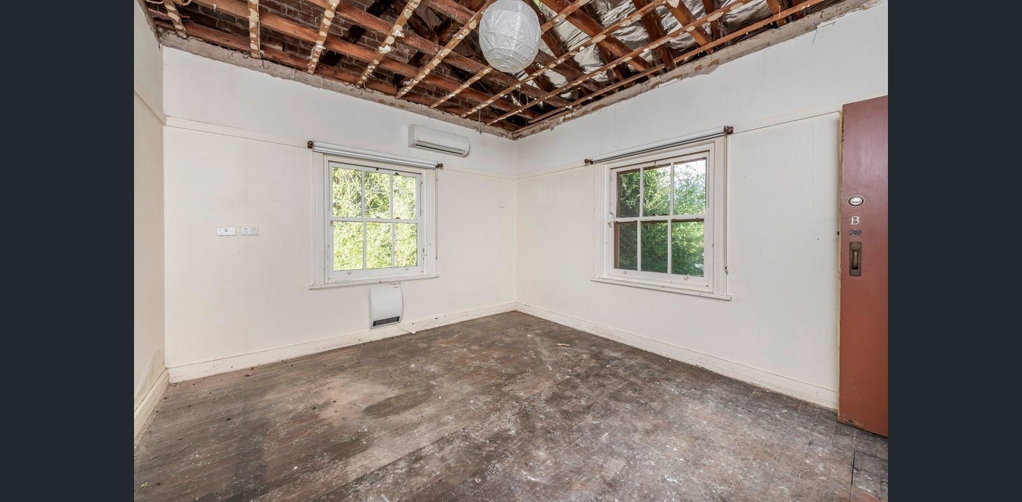 Empty Room With Unfinished Ceiling, Two Windows, and Stained Floor. Brown Door on the Right — Elimar Construction in Goulburn, NSW