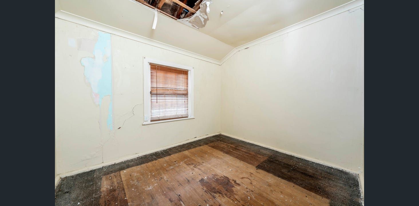 Empty Room With Damaged Ceiling, Walls, and Wooden Floor. Window With Blinds — Elimar Construction in Goulburn, NSW