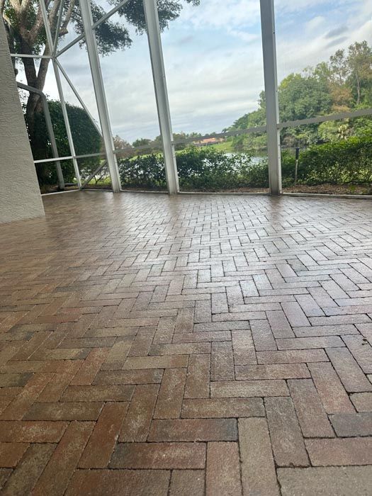 a brick floor with a herringbone pattern in a room with a lot of windows