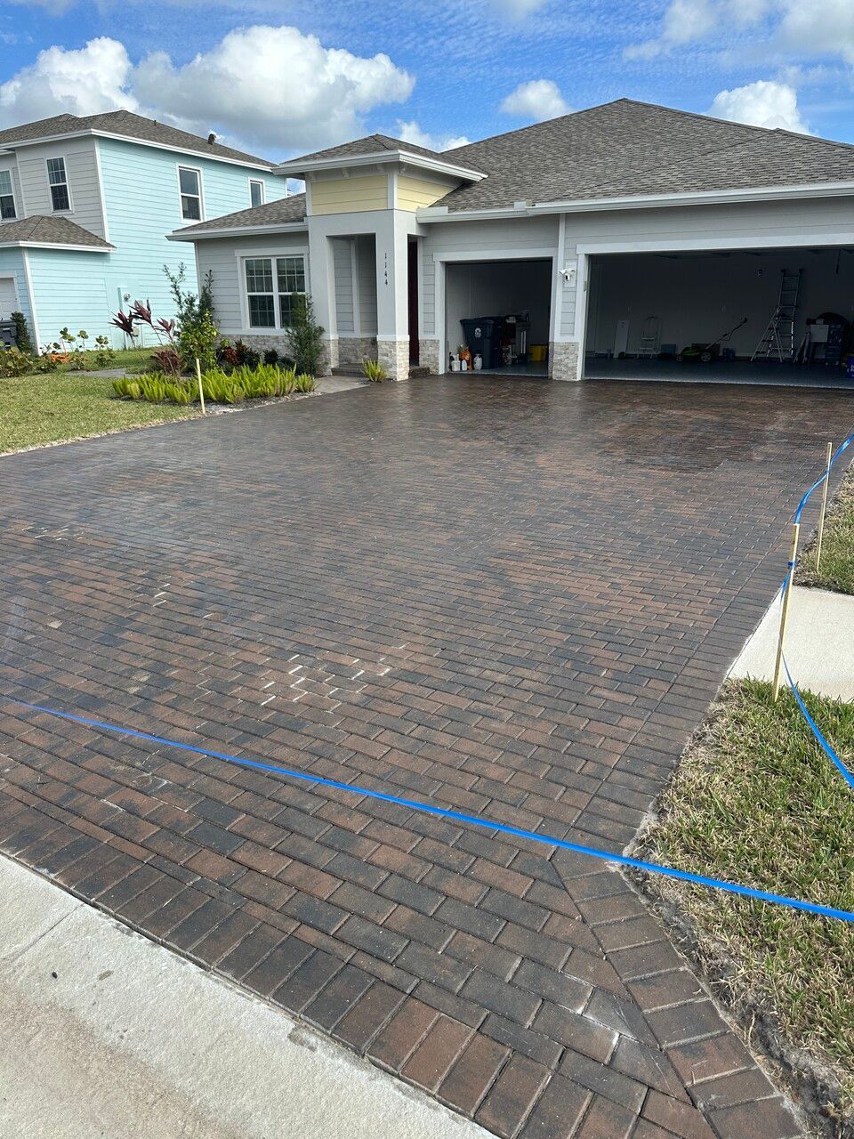 a brick driveway in front of a house with a blue line on it