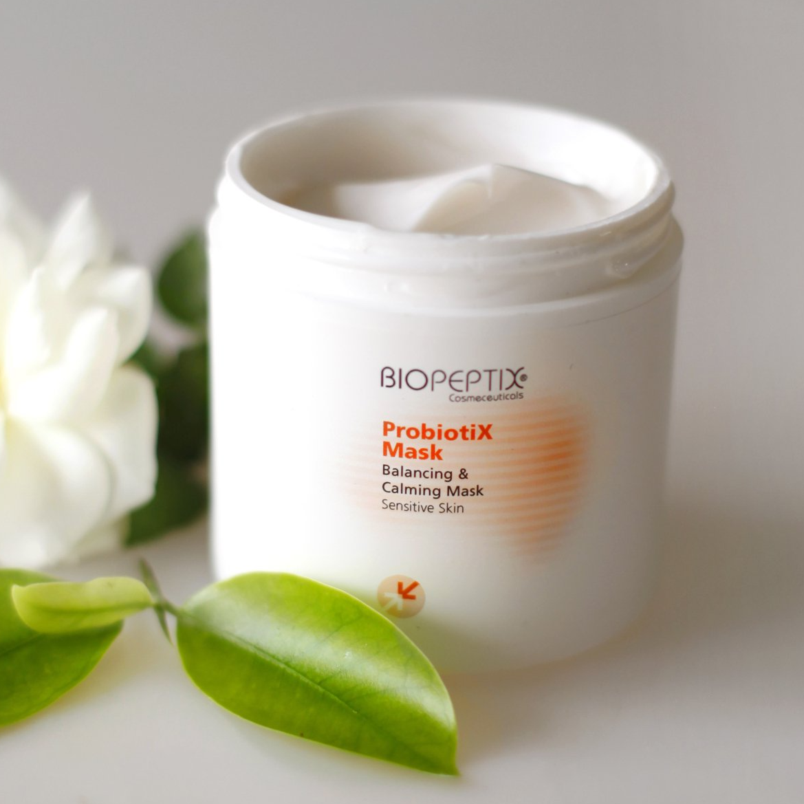 A jar of biopeptide probiotics next to a flower