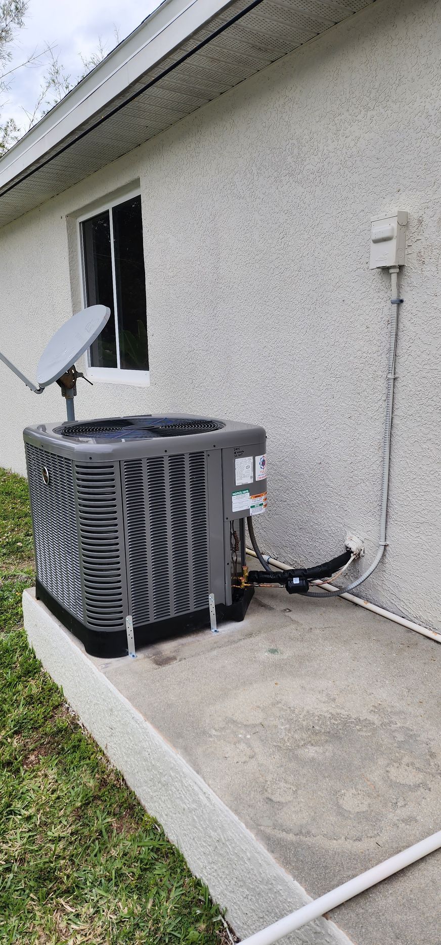 An air conditioner is sitting on the side of a house next to a window.