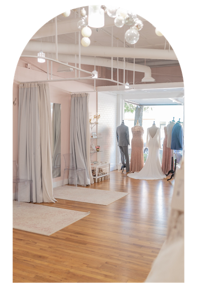 Bright boutique interior with wooden floors, hanging dresses, and soft white decor