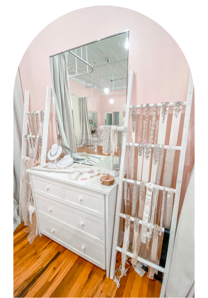 White dresser with mirror in a pink bedroom, styled with decor and a ladder shelf nearby