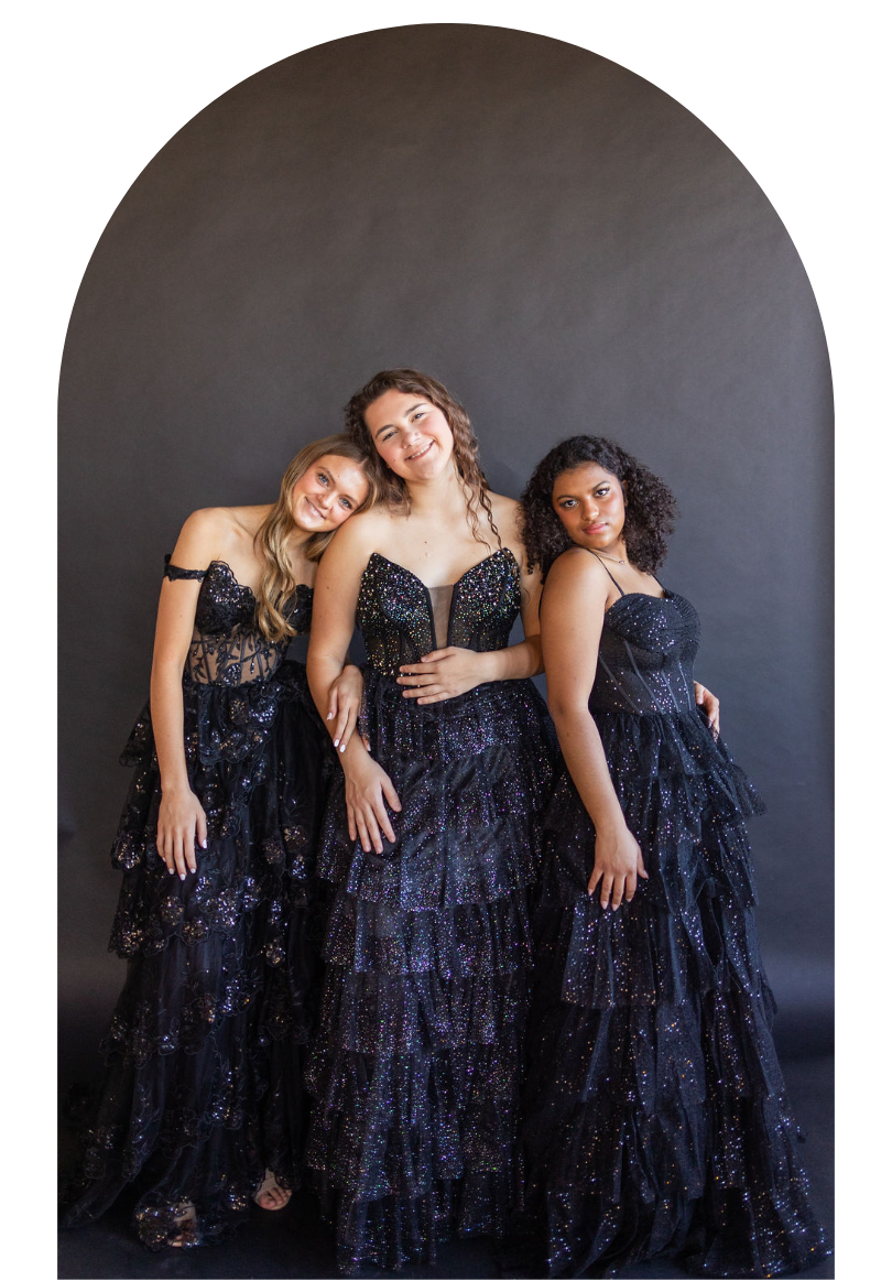 Three women in black sequined gowns posing against a dark arched backdrop